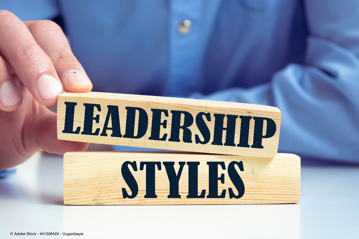 Eine Hand stapelt zwei Holzblöcke mit der Aufschrift Leadership Styles und symbolisiert unterschiedliche Führungsstile im beruflichen Umfeld.